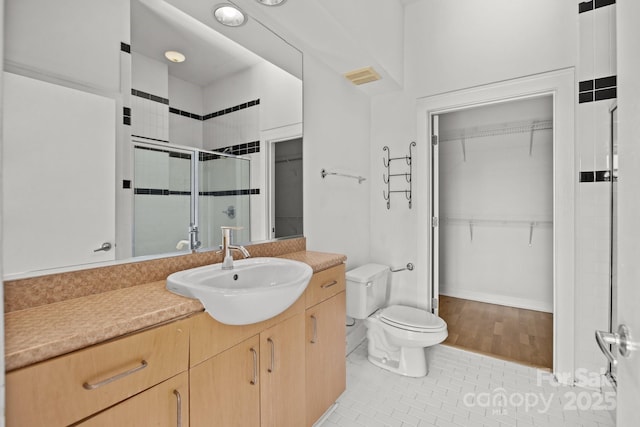 bathroom featuring vanity, toilet, a shower with shower door, and tile patterned flooring