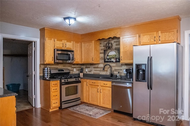 kitchen with sink, appliances with stainless steel finishes, dark hardwood / wood-style floors, and tasteful backsplash