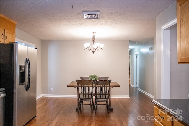 dining room featuring an inviting chandelier, a textured ceiling, and dark wood-type flooring