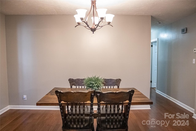 dining area featuring a chandelier, dark hardwood / wood-style floors, and a textured ceiling