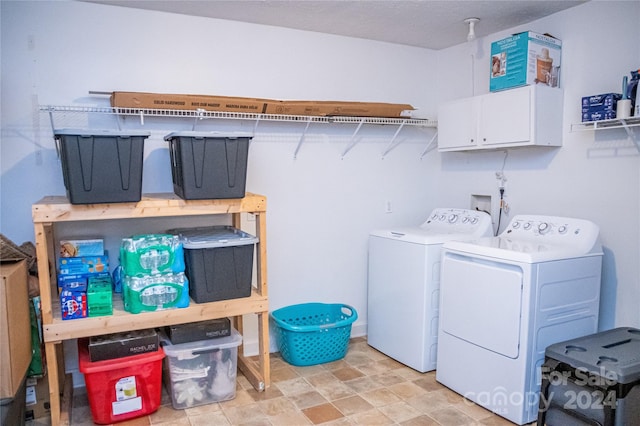 clothes washing area featuring cabinets and washer and dryer