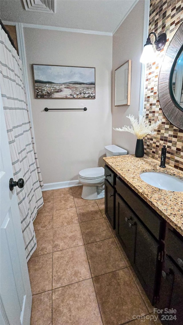 bathroom featuring tasteful backsplash, toilet, tile patterned floors, vanity, and crown molding