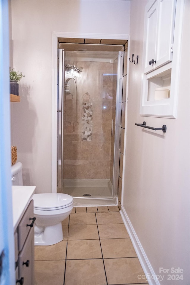 bathroom with vanity, toilet, tile patterned floors, and a shower with door