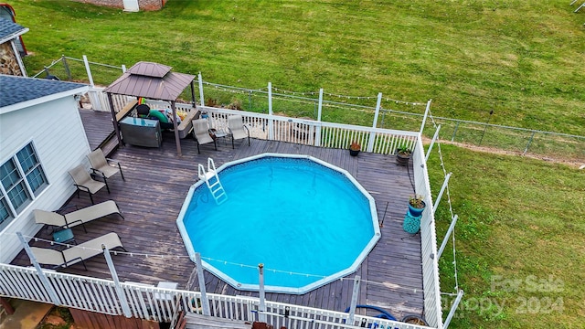 view of pool with a wooden deck and a yard