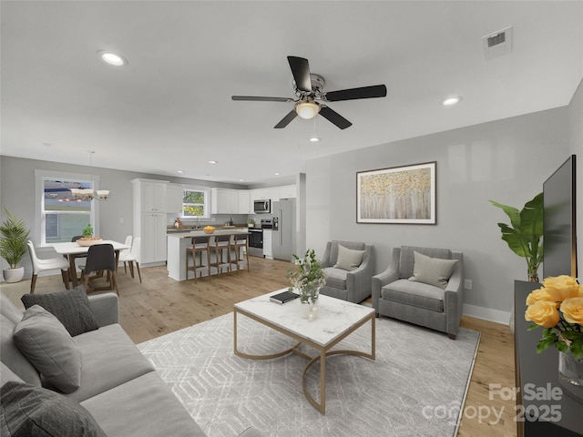 living room featuring ceiling fan and light hardwood / wood-style floors