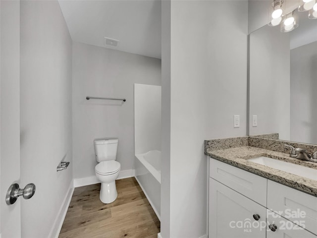 bathroom with hardwood / wood-style floors, vanity, toilet, and a washtub