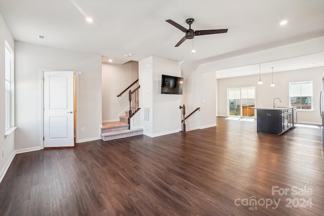 unfurnished living room featuring ceiling fan, sink, and dark hardwood / wood-style flooring