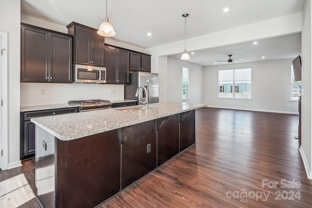 kitchen featuring an island with sink, dark brown cabinetry, stainless steel appliances, and pendant lighting