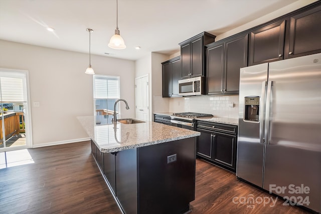 kitchen with sink, stainless steel appliances, decorative light fixtures, dark hardwood / wood-style floors, and a kitchen island with sink