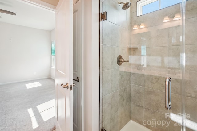 bathroom featuring ceiling fan and an enclosed shower