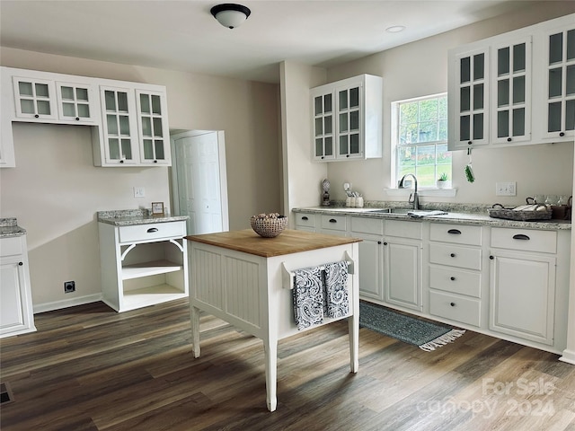 kitchen with dark wood-type flooring, light stone counters, sink, and white cabinets