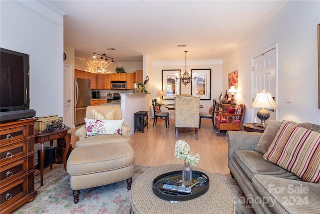 living room featuring a chandelier, light hardwood / wood-style flooring, and crown molding