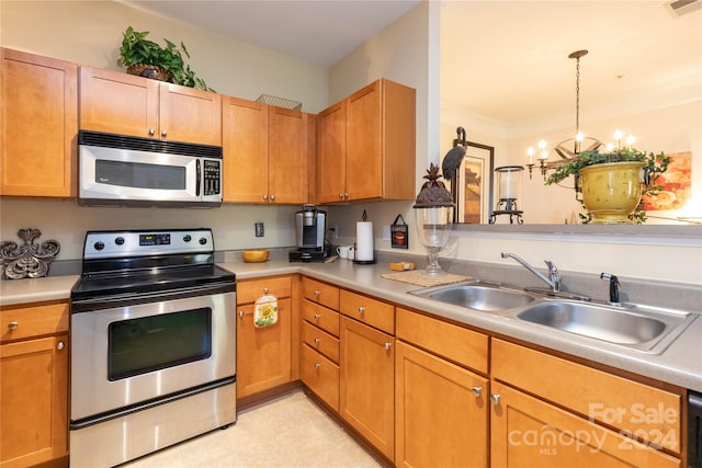 kitchen with appliances with stainless steel finishes, sink, pendant lighting, crown molding, and an inviting chandelier