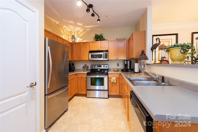 kitchen with appliances with stainless steel finishes, ornamental molding, and sink