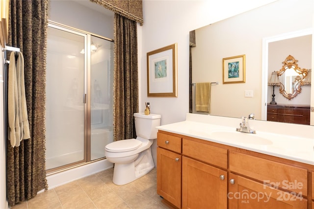 bathroom featuring vanity, toilet, tile patterned flooring, and an enclosed shower