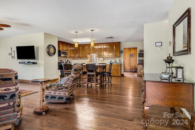 living room featuring a textured ceiling, ceiling fan, sink, and dark hardwood / wood-style flooring