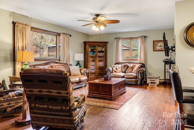 living room with a textured ceiling, hardwood / wood-style flooring, and ceiling fan