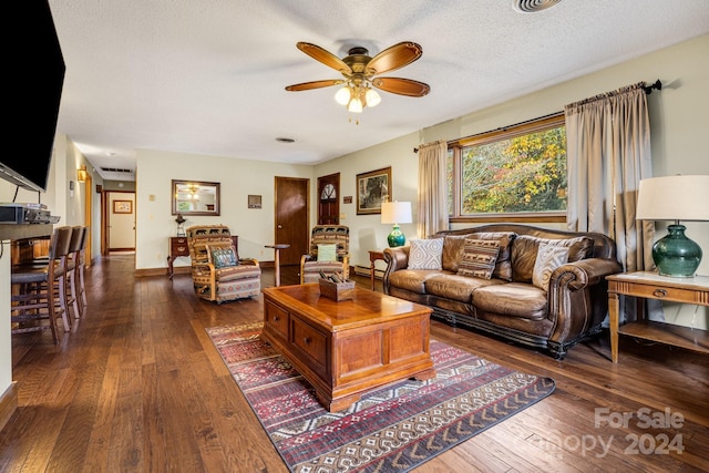 living room with dark wood-type flooring, ceiling fan, and a textured ceiling