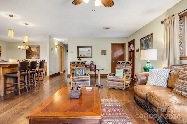 living room featuring dark wood-type flooring and ceiling fan with notable chandelier