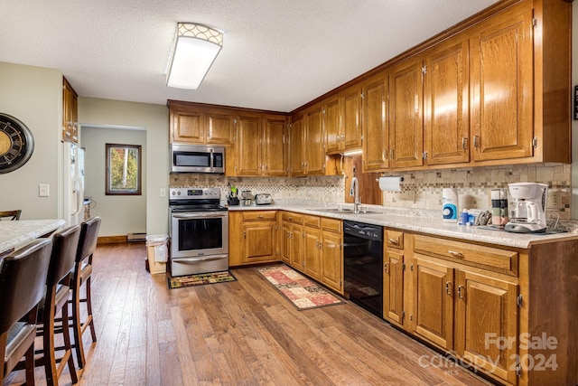 kitchen with backsplash, hardwood / wood-style floors, sink, appliances with stainless steel finishes, and a textured ceiling