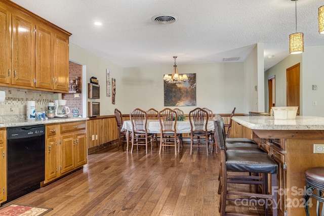 kitchen featuring a kitchen bar, black dishwasher, decorative light fixtures, and dark hardwood / wood-style floors