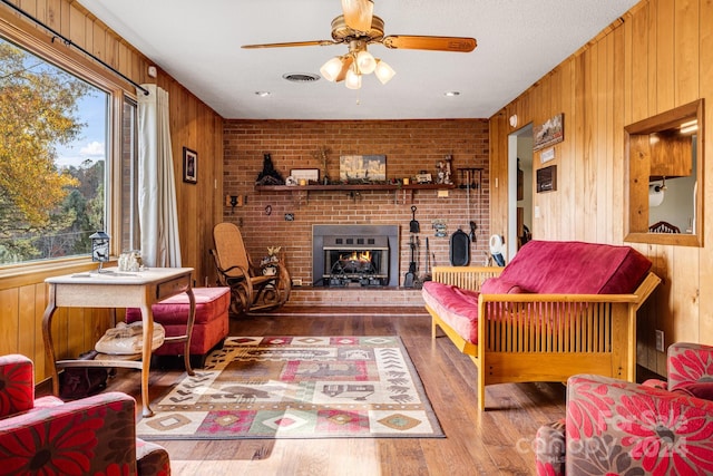 living room featuring hardwood / wood-style flooring, wooden walls, brick wall, and ceiling fan