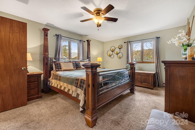 bedroom with light carpet, multiple windows, a textured ceiling, and ceiling fan