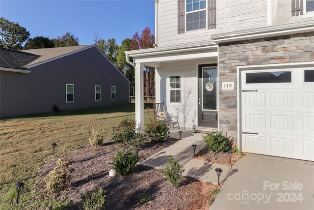 view of exterior entry with a yard and a garage