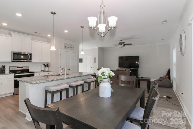 dining space featuring ornamental molding, sink, light hardwood / wood-style flooring, and ceiling fan with notable chandelier