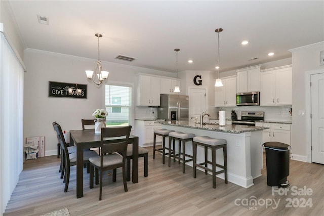 kitchen featuring white cabinetry, appliances with stainless steel finishes, light wood-type flooring, and a center island with sink