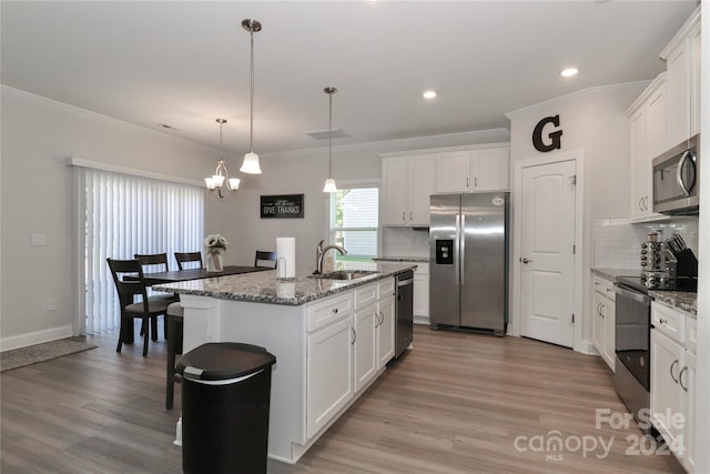 kitchen with wood-type flooring, sink, an island with sink, stainless steel appliances, and white cabinets