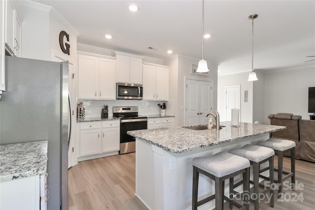 kitchen with backsplash, sink, decorative light fixtures, white cabinetry, and appliances with stainless steel finishes