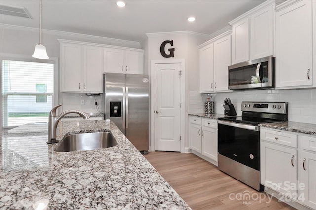 kitchen with sink, white cabinets, appliances with stainless steel finishes, light hardwood / wood-style floors, and tasteful backsplash