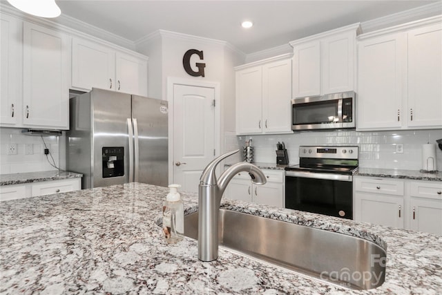 kitchen with light stone countertops, decorative backsplash, white cabinetry, and stainless steel appliances