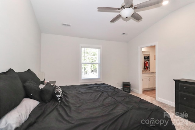 carpeted bedroom featuring connected bathroom, vaulted ceiling, and ceiling fan