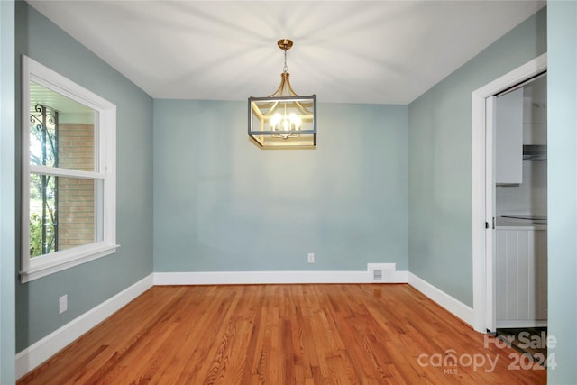 unfurnished room featuring an inviting chandelier and hardwood / wood-style flooring