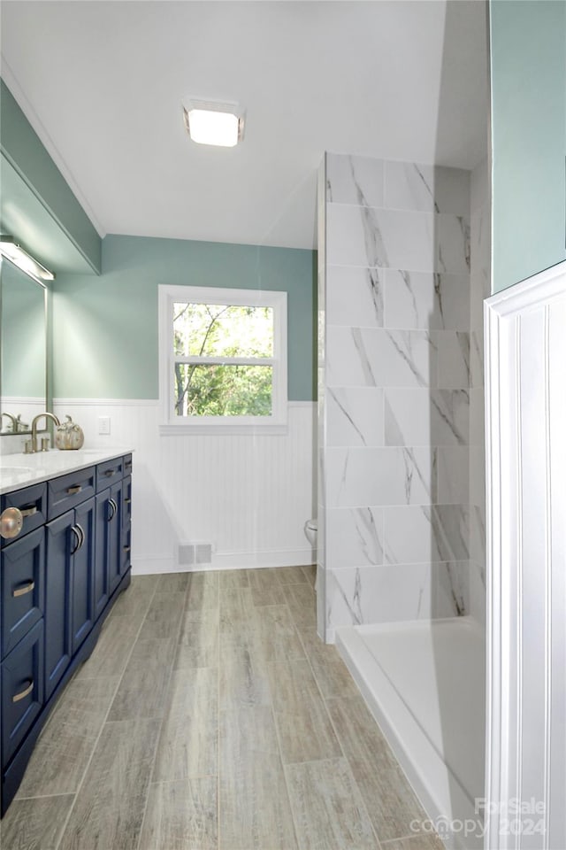 bathroom with vanity, toilet, and tiled shower