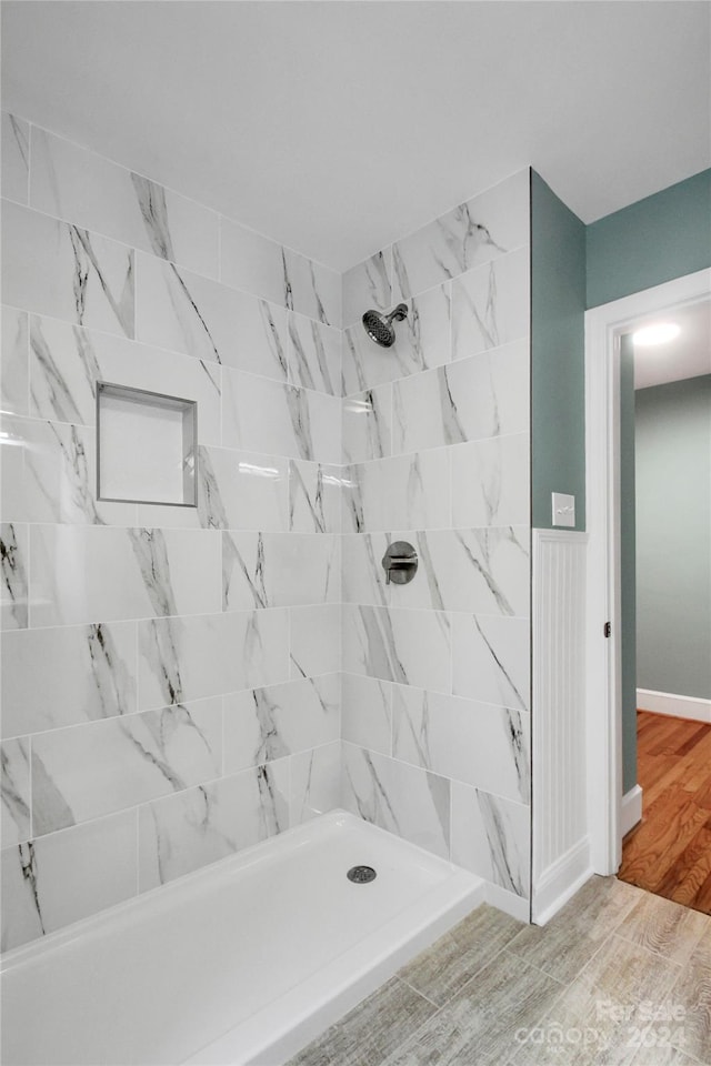 bathroom with tiled shower and wood-type flooring