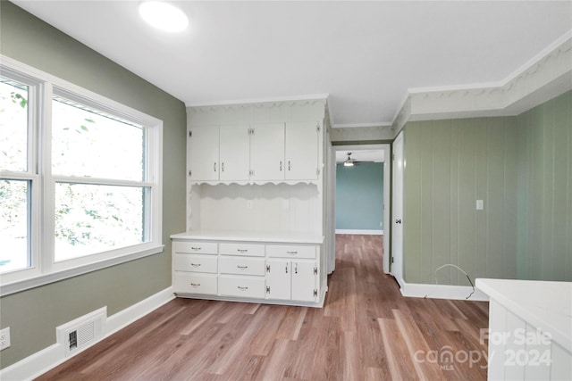 interior space with ornamental molding, white cabinets, light wood-type flooring, and ceiling fan