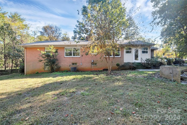 rear view of house with a lawn and cooling unit