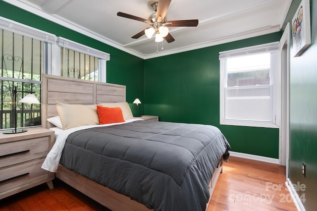 bedroom with crown molding, wood-type flooring, and ceiling fan