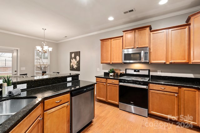 kitchen with dark stone counters, crown molding, appliances with stainless steel finishes, light hardwood / wood-style floors, and a chandelier