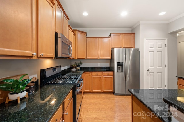 kitchen featuring dark stone countertops, light wood-type flooring, ornamental molding, and appliances with stainless steel finishes