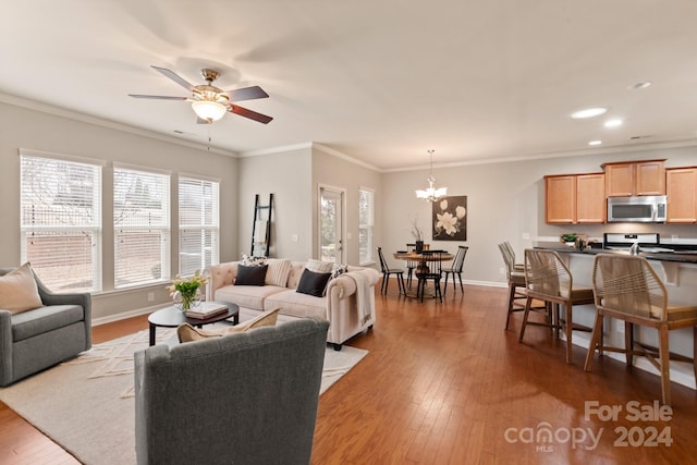 living room with ceiling fan with notable chandelier, ornamental molding, and light hardwood / wood-style flooring