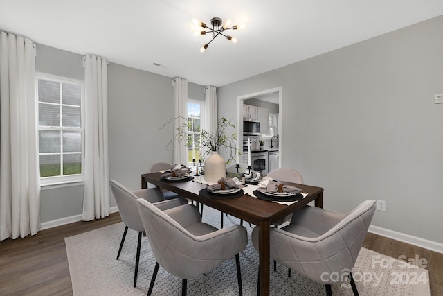 dining space featuring dark wood-type flooring, a healthy amount of sunlight, an inviting chandelier, and sink