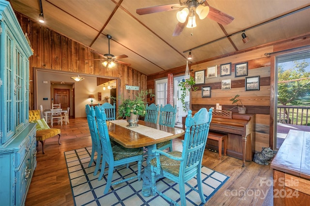 dining room featuring wood-type flooring, wooden walls, and vaulted ceiling