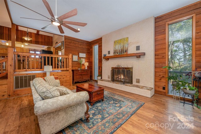 living room featuring light hardwood / wood-style flooring, ceiling fan, and wood walls