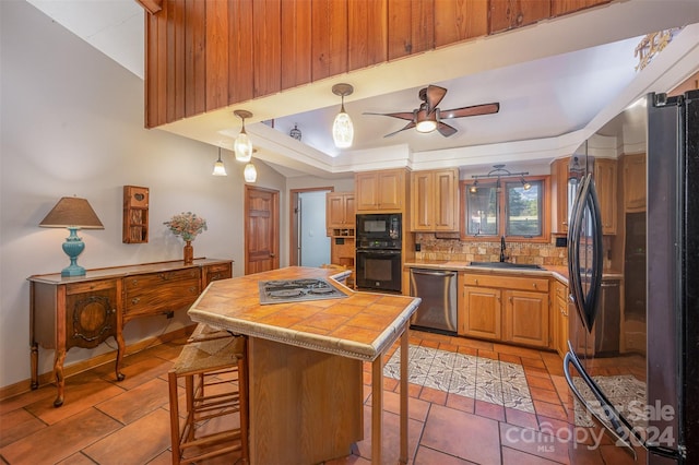 kitchen with a center island, black appliances, sink, decorative backsplash, and a breakfast bar area