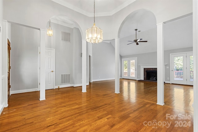 unfurnished living room with high vaulted ceiling, wood-type flooring, plenty of natural light, and ceiling fan with notable chandelier