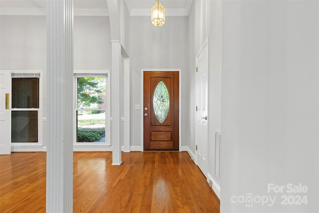 foyer entrance featuring crown molding, a high ceiling, and hardwood / wood-style floors